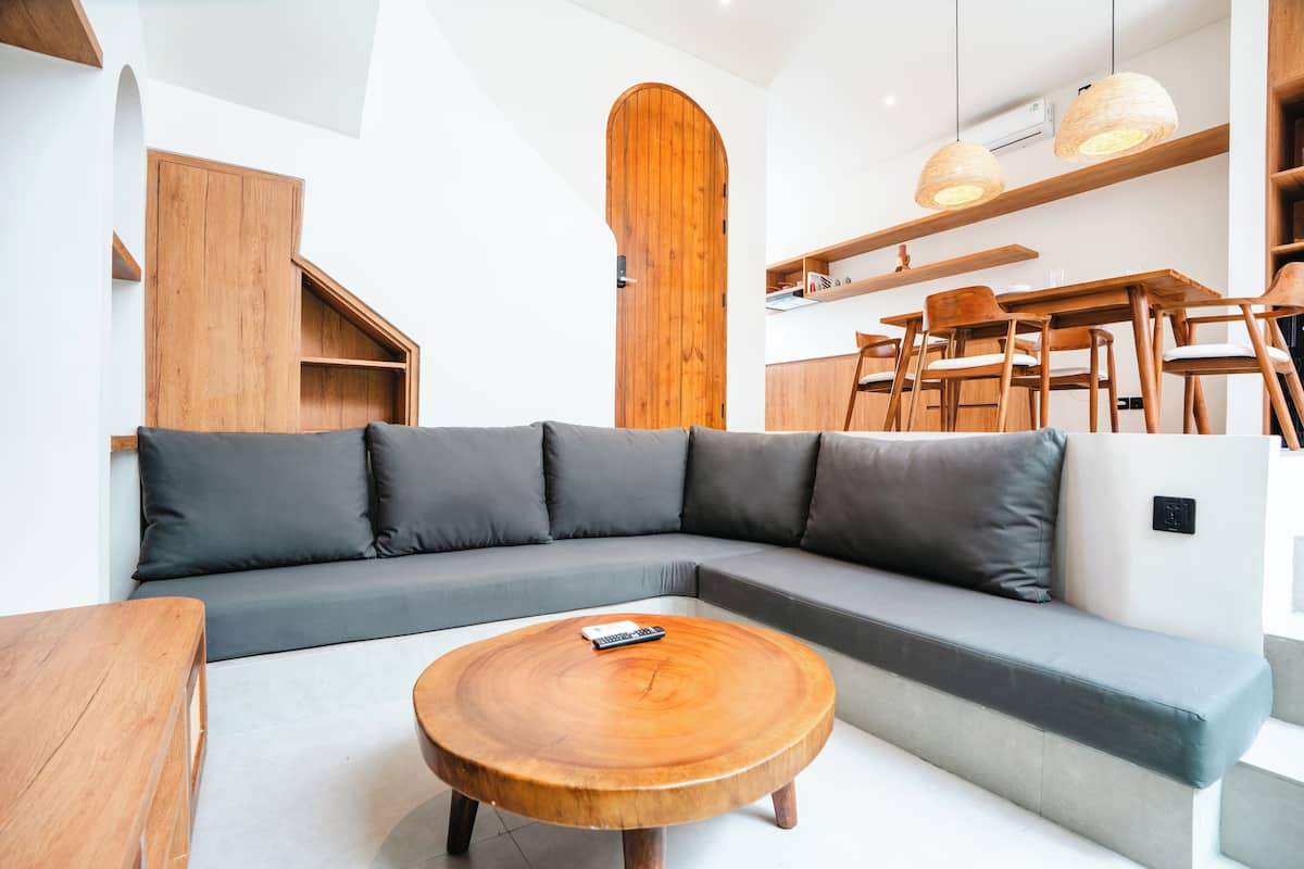 A modern living room with a wooden coffee table, grey sofa, and wooden cabinets.