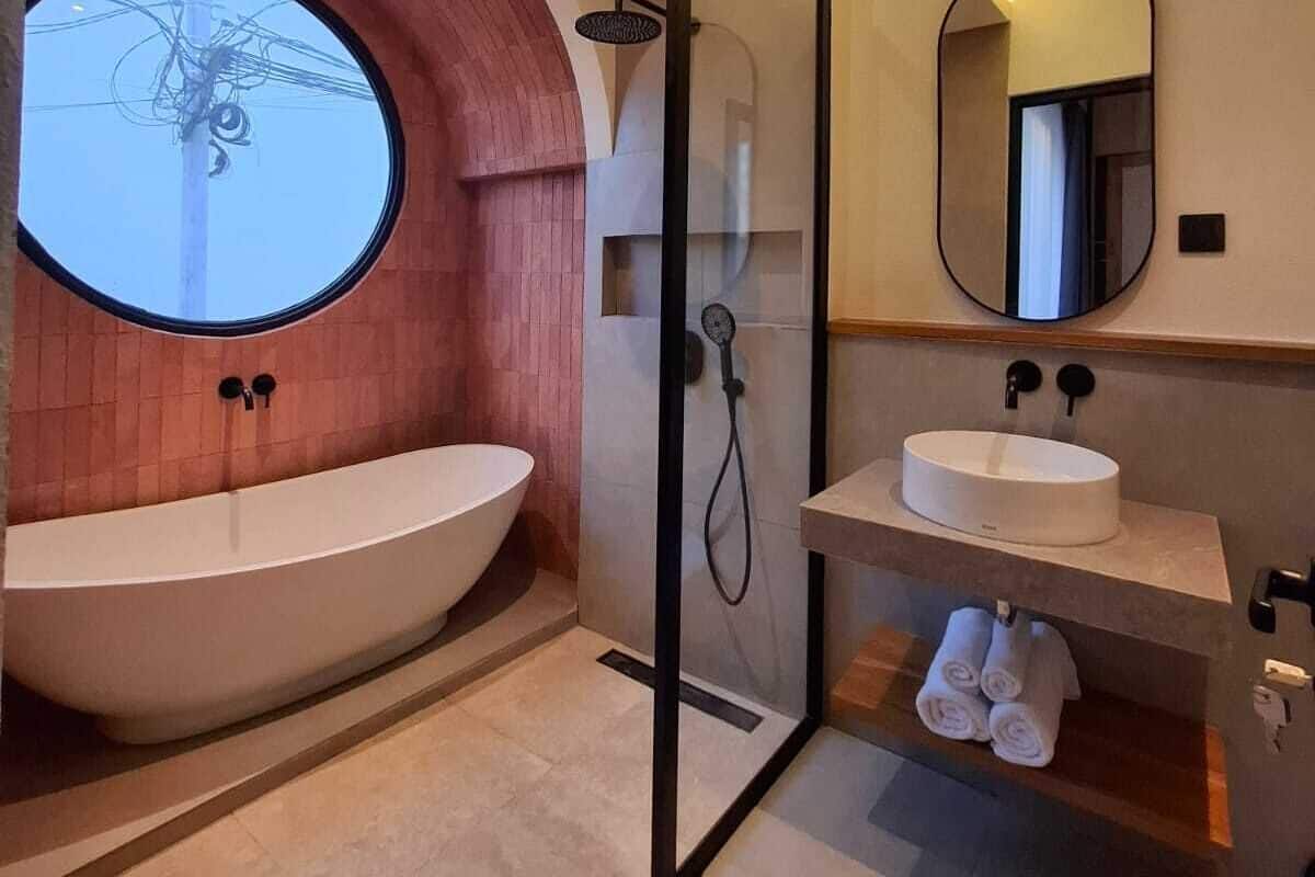 A modern bathroom with a freestanding bathtub, a glass-enclosed shower, and a round mirror.