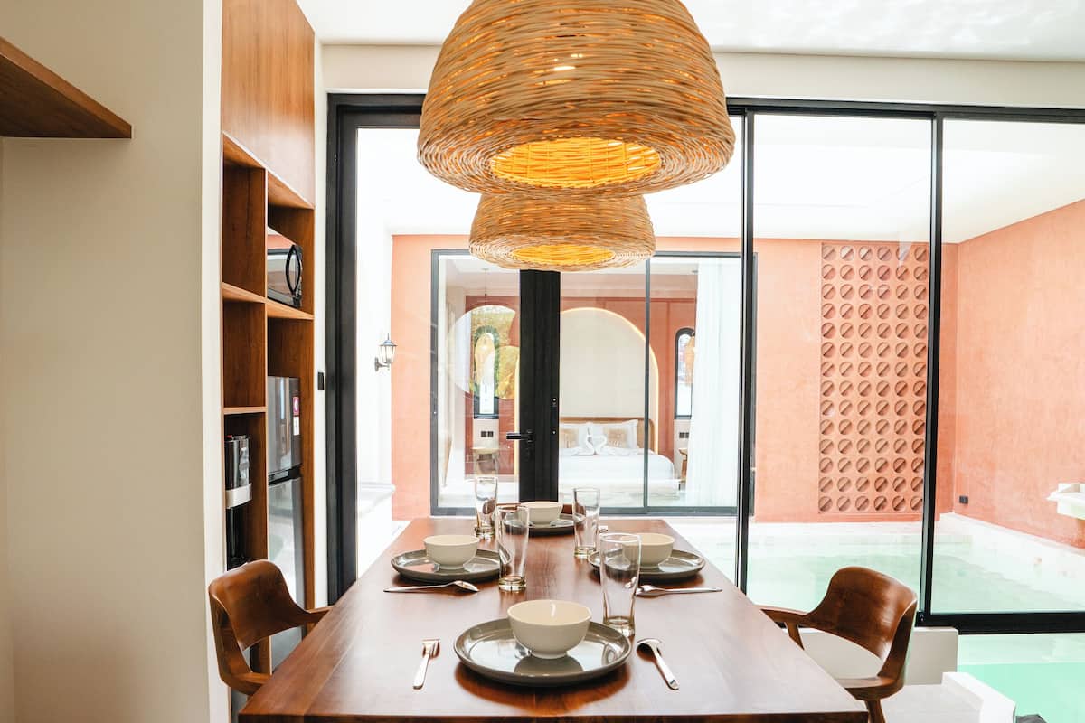 A dining area with a wooden table, chairs, and a large woven pendant light.