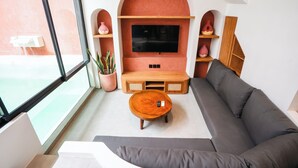 A modern living room with a large TV, a wooden coffee table, and a grey sofa.