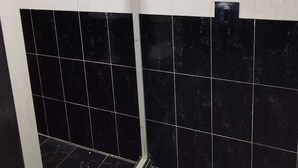 Een badkamer met zwart-wit betegelde muren, een douchegedeelte en een deur met raam.