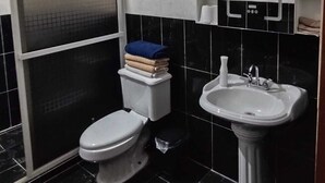 Een badkamer met toilet, wastafel en douchecabine.