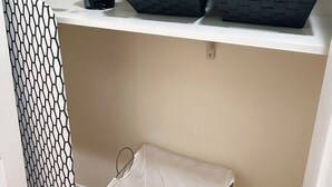 A laundry area with a basket of white towels, a blue water bottle, and a black basket with a towel. - Luxurious 3-bedroom 2 bath near NYC train station, EWR. (Newark)