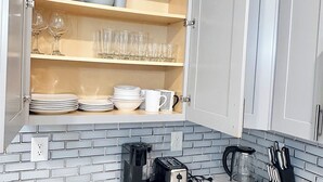 A kitchen with white cabinets, a tiled backsplash, a coffee maker, a toaster, a kettle, and a knife block. - Luxurious 3-bedroom 2 bath near NYC train station, EWR. (Newark)