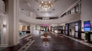 Een ruime hotellobby met een kroonluchter in het midden, een receptiebalie en een zithoek.