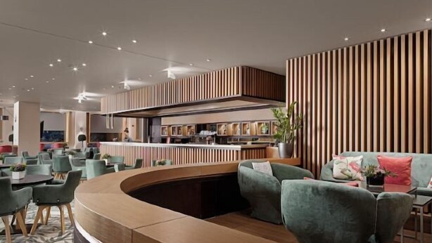 Een modern interieur met een gebogen zithoek, een bar en een keuken op de achtergrond.