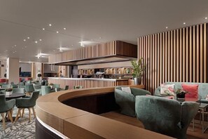 Un interior moderno con una zona de estar curvada, una barra y una cocina al fondo.