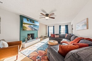A living room with a sofa, a coffee table, a fireplace, and a ceiling fan. - Space for 10+ and Fenced Yard, The Indigo House! (North Charleston)