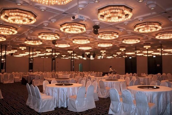 A banquet hall with round tables, white tablecloths, and chandeliers. - Concorde Hotel Singapore (Singapore)