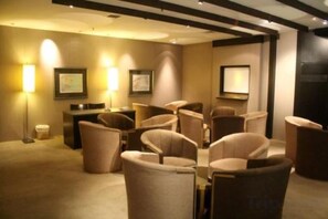 Habitación de hotel con zona de estar, escritorio y lámparas de pared.