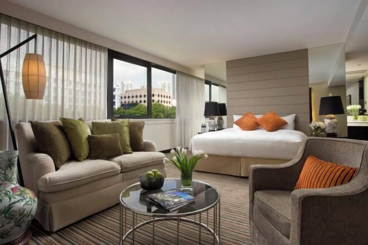 A hotel room with a bed, a sofa, a coffee table, and a chair.