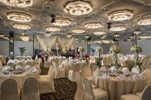 Un salón de banquetes con mesas redondas, sillas y candelabros.