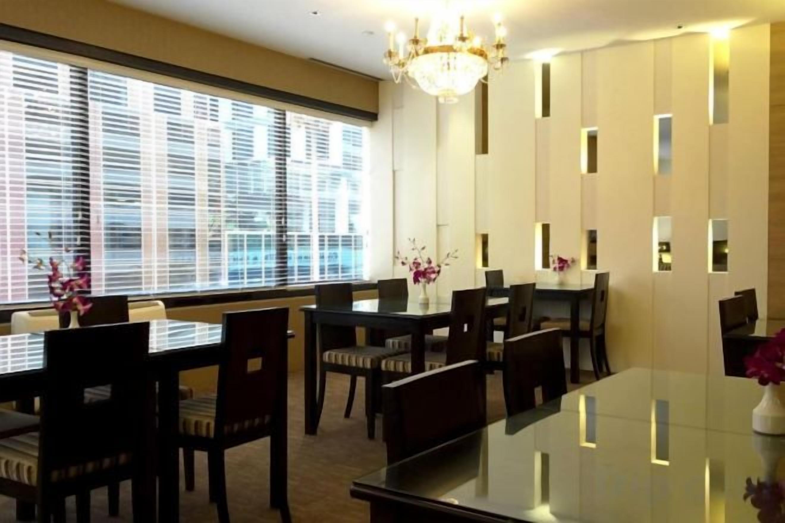 A dining area with a glass table, chairs, and a chandelier.