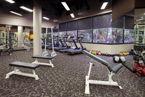 Un gimnasio con cintas de correr, máquinas de pesas y bancos.