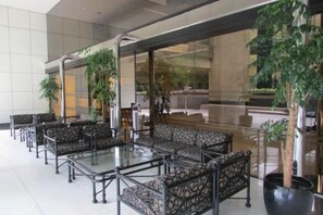 Un vestíbulo con arreglos de asientos, ventanas amplias y plantas de interior.