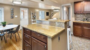 Una cocina con armarios de madera, encimera de granito y salpicadero azulejado.