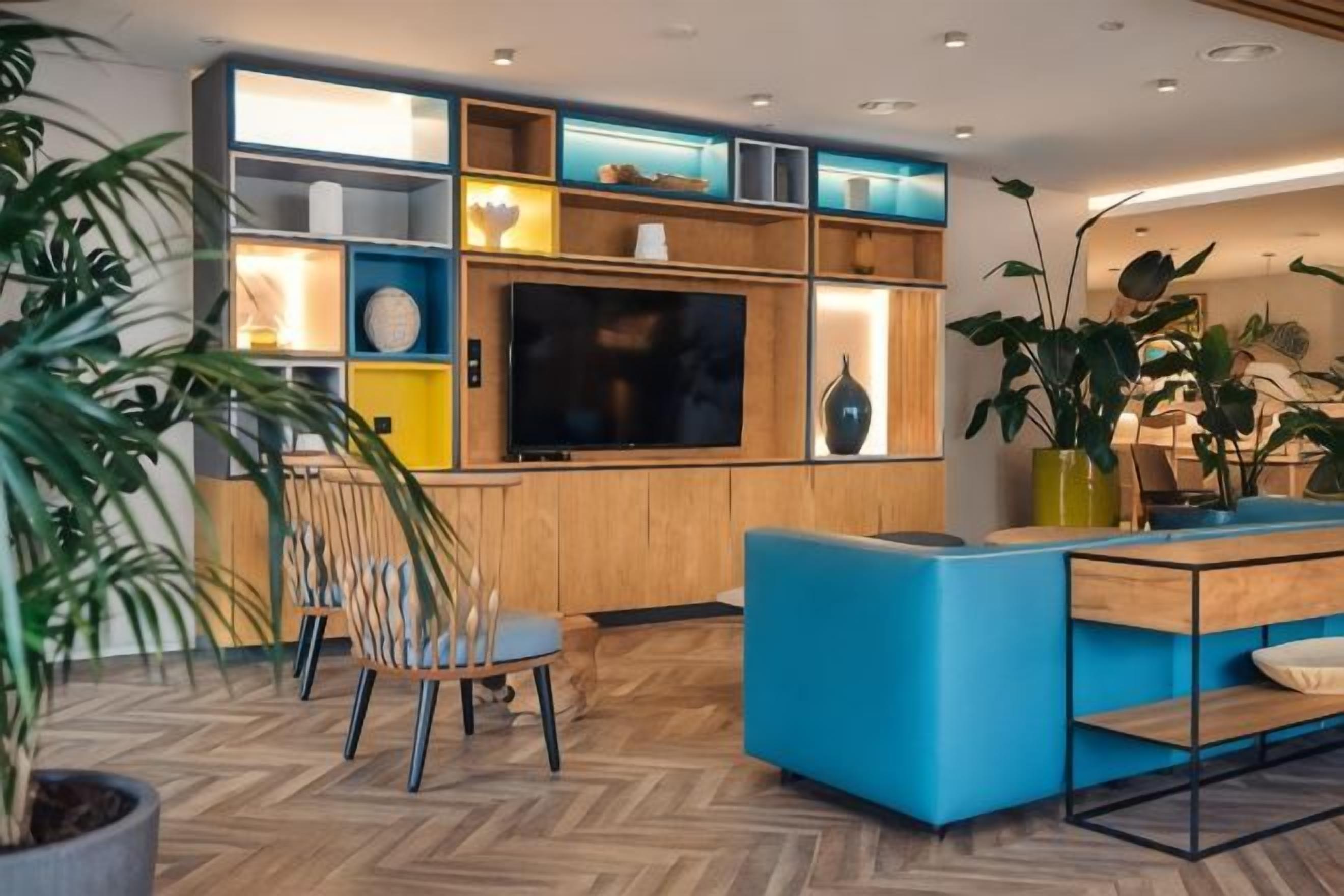 Ein modernes Wohnzimmer mit Fernseher, Holzregalen und blauer Möbel.