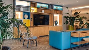 Ein modernes Wohnzimmer mit Fernseher, Holzregalen und blauer Möbel.