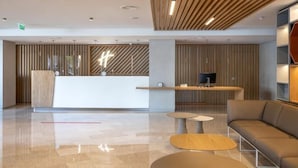 A modern lobby with a reception desk, seating area, and a television. - Holiday Inn LISBON by IHG (Lisbon)