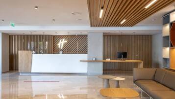 A modern lobby with a reception desk, seating area, and a television.