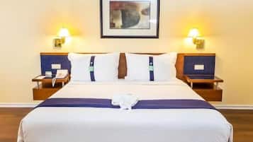 Una camera d'albergo con un letto grande, due comodini, un quadro incorniciato appeso al muro e due lampade a parete.