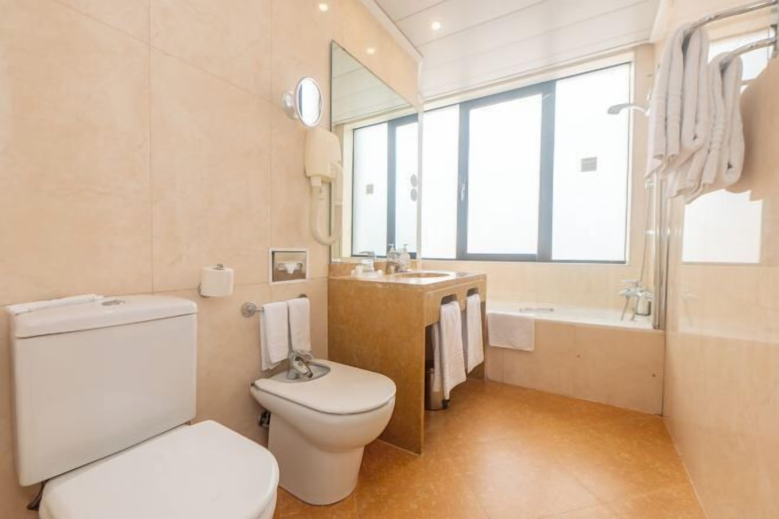 Une salle de bain comprenant des toilettes, un bidet, un lavabo et une baignoire.