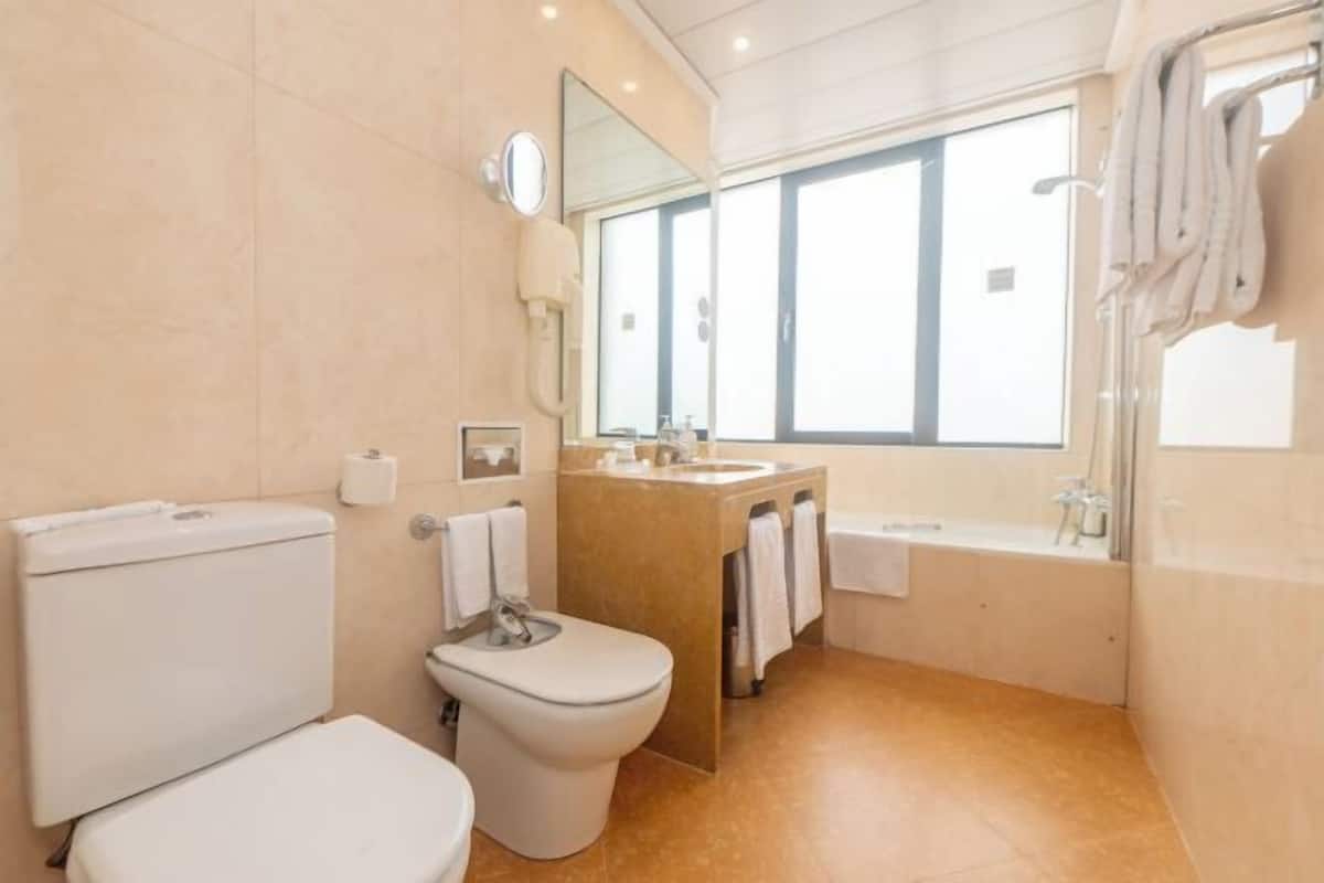 A bathroom with a toilet, bidet, sink, and bathtub.