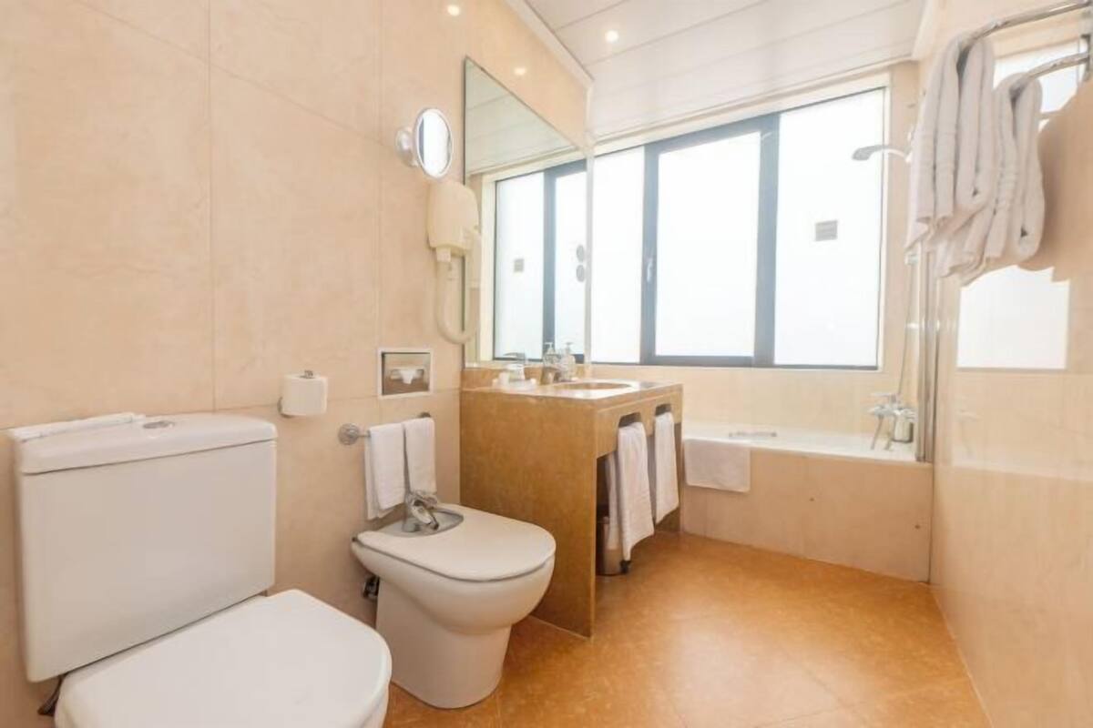 A bathroom with a toilet, bidet, sink, and bathtub.