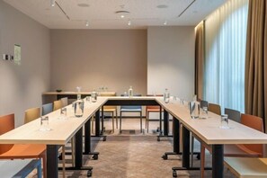 A conference room with a long table, chairs, and a window with curtains.