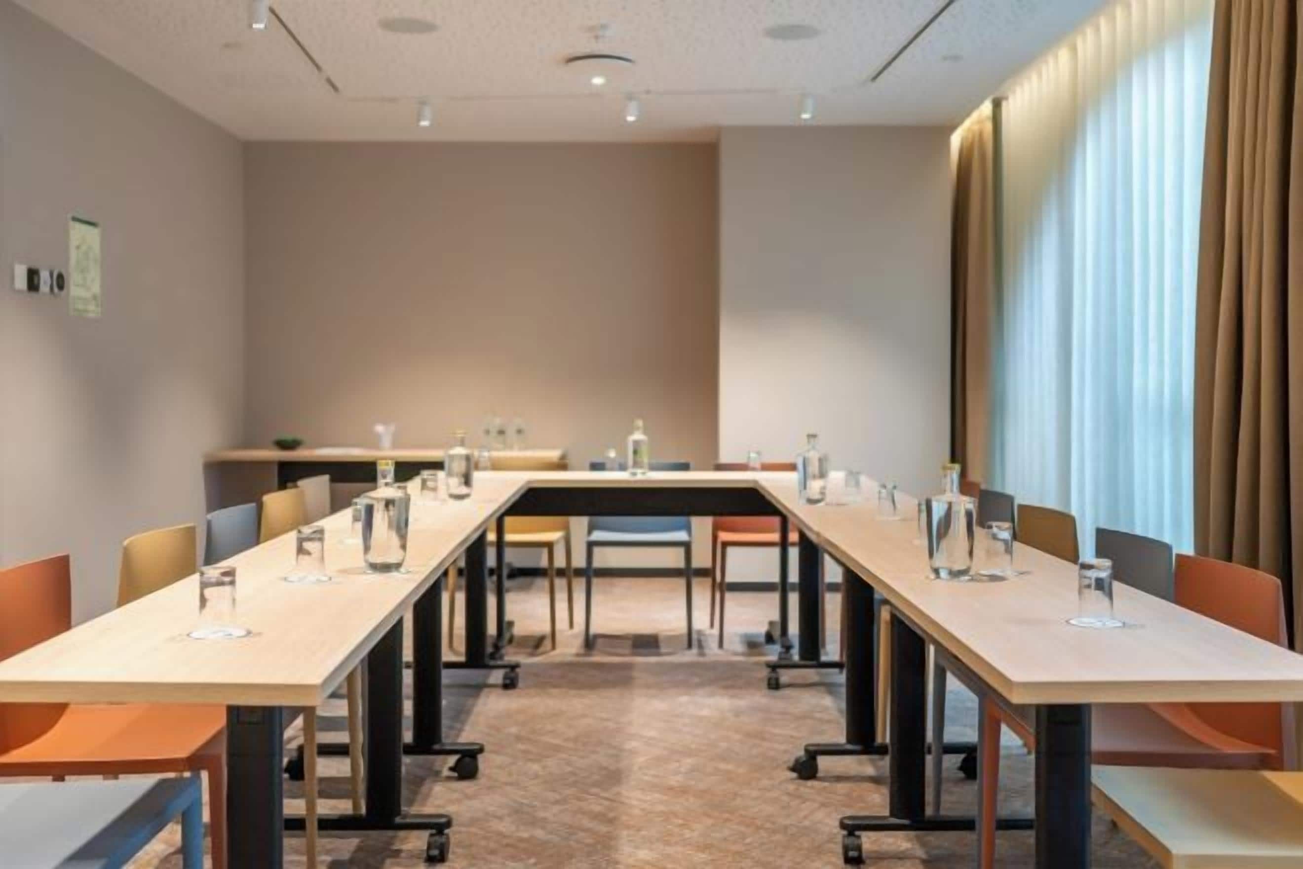 Uma sala de conferências com uma mesa comprida, cadeiras e piso coberto por carpete.