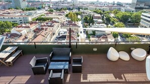 A rooftop terrace with outdoor seating, a city view, and a glass railing. - Holiday Inn LISBON by IHG (Lisbon)