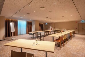 Kokoushuone, jossa on pitkä pöytä, tuoleja, projektori ja valkotaulu.