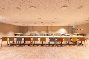 Une salle de conférence avec une longue table et des chaises, un plafond orné de motifs et un sol recouvert de moquette.