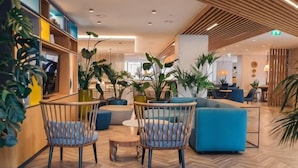 A modern lobby with seating, plants, and a wooden floor. - Holiday Inn LISBON by IHG (Lisbon)