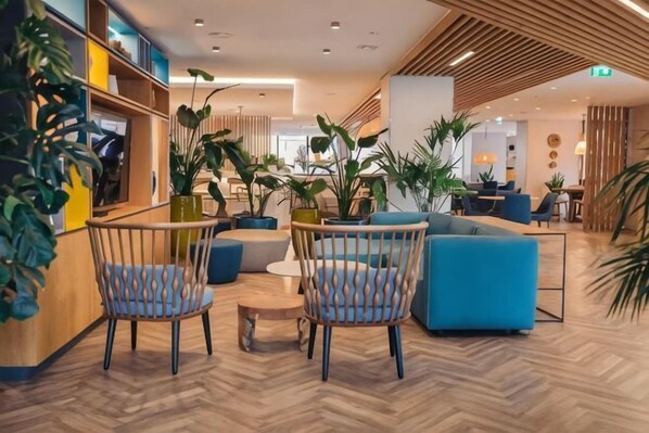 A modern lobby with seating, plants, and a wooden floor.