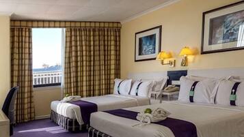Ein Hotelzimmer mit zwei Betten, einem Schreibtisch, einem Stuhl und einem Fenster mit Vorhängen.