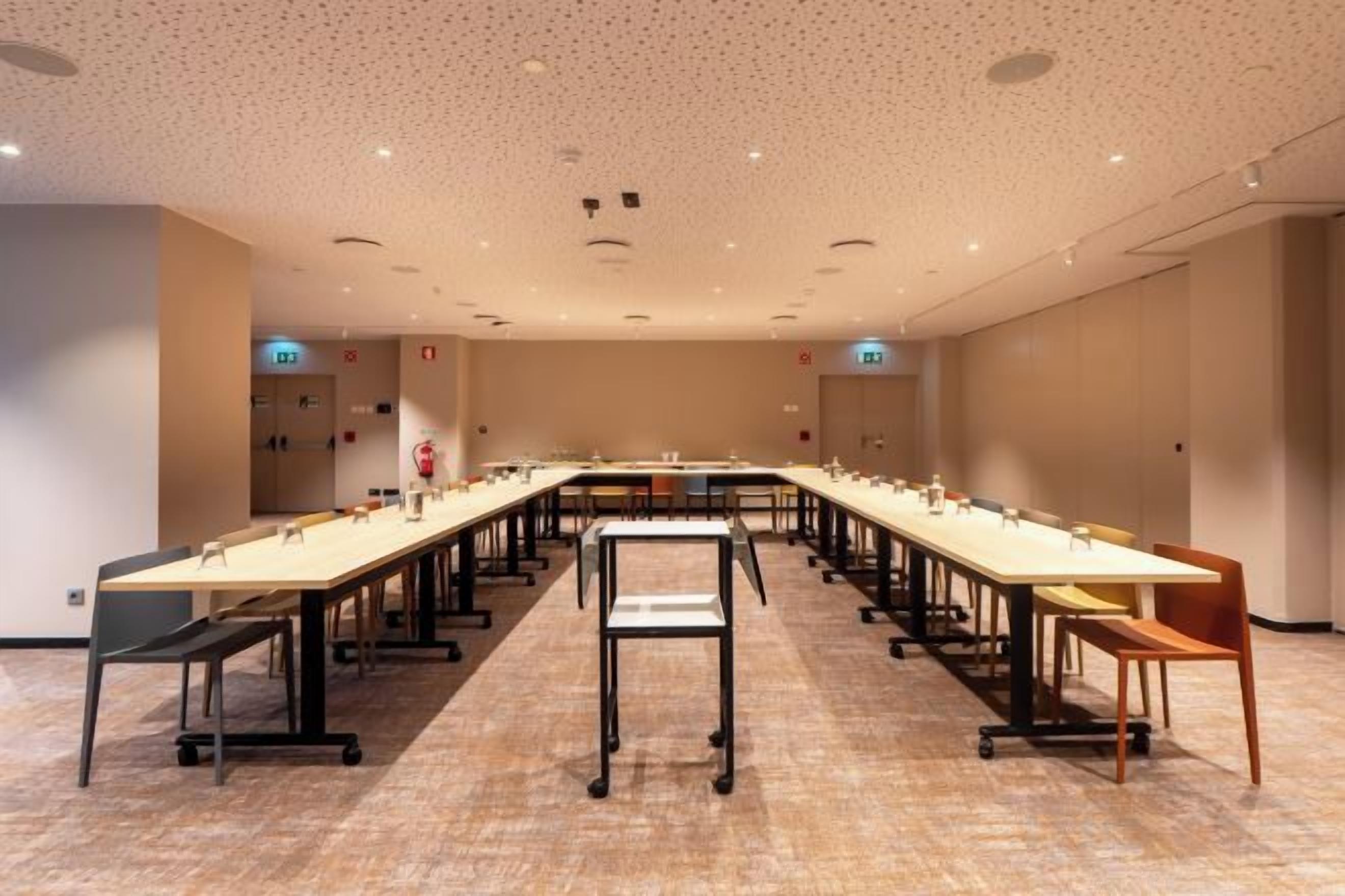Een vergaderruimte met een lange tafel, stoelen en een vloerkleed.