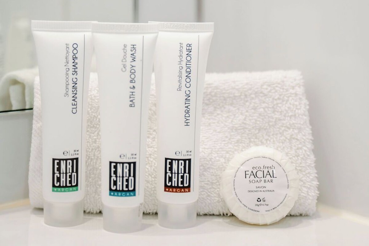 Three ENRICHED BARGAN products and a white towel on a bathroom counter.