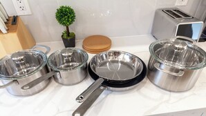 Uma bancada de cozinha com utensílios de aço inoxidável, uma torradeira e uma pequena planta em vaso.