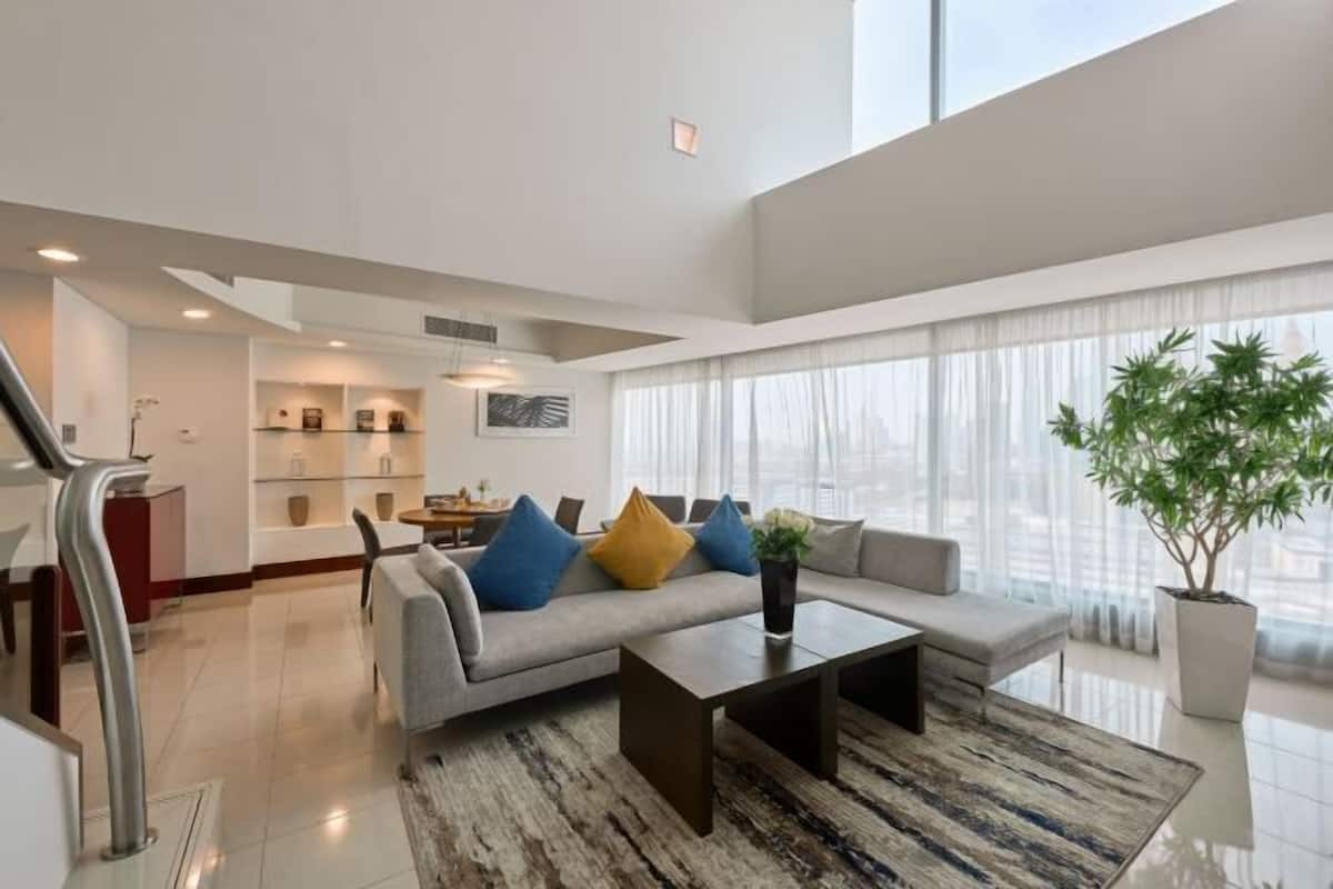 A modern living room with a sofa, coffee table, and a large window with curtains.