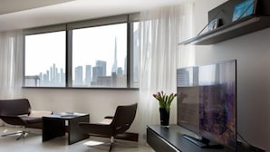 Een moderne woonkamer met een groot raam, een flatscreen televisie en twee leren fauteuils.