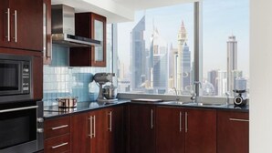 Een moderne keuken met donkere houtkasten, roestvrijstalen apparatuur en een groot raam met uitzicht op de stadshemel.
