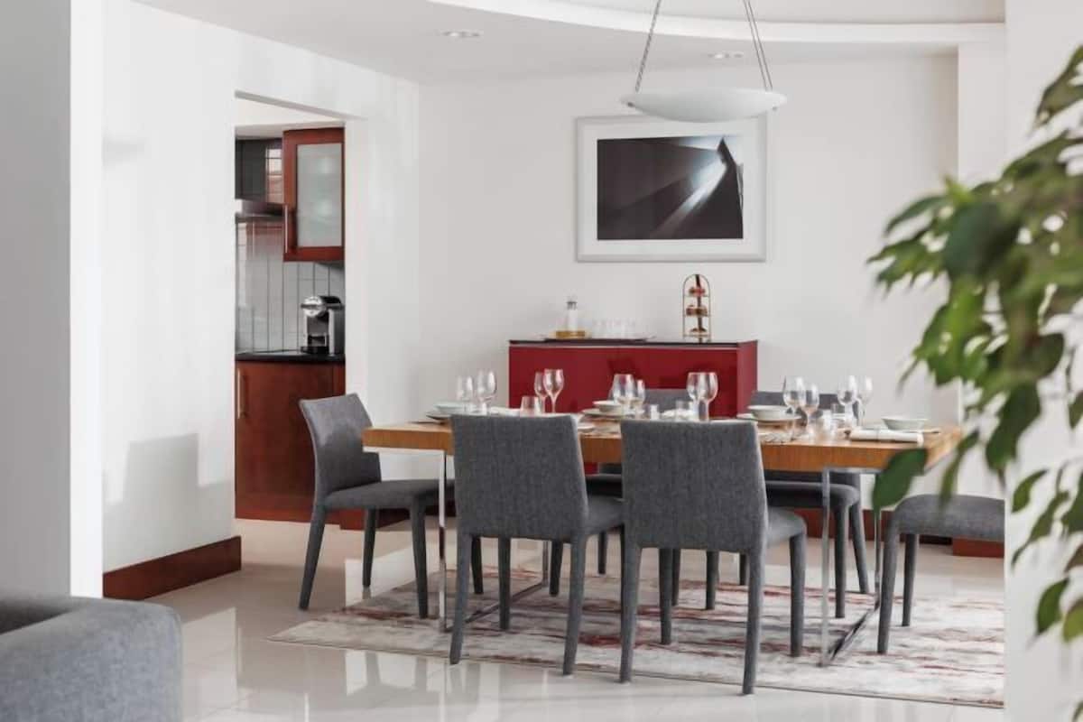 A modern dining area with a wooden table, grey chairs, and a red cabinet.
