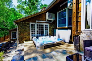 A hot tub in a stone-walled outdoor area with a wooden deck, a stone wall, and a window. - Riverfront Cottage w/ Heated Pool, Hot Tub & Fireplace, 35 min to NYC (Greenwich)