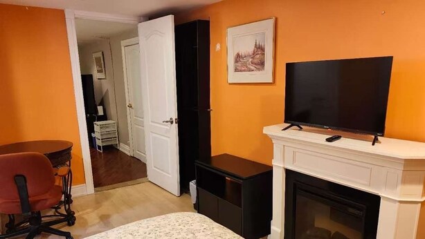 Een slaapkamer met een bed, een televisie, een open haard en een deur naar een andere kamer.