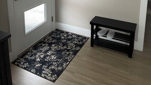 A room with a door, a wall-mounted mirror, a bench, and a patterned rug. - Adorable 1-bedroom Guesthouse for Travel Professional (Kennewick)