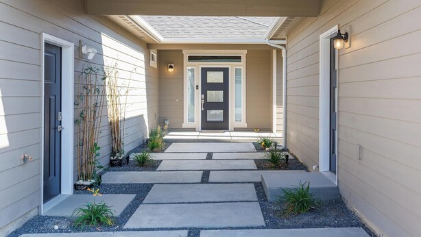 A house entrance with a dark front door, a covered porch, and a pathway leading to the door. - Adorable 1-bedroom Guesthouse for Travel Professional (Kennewick)