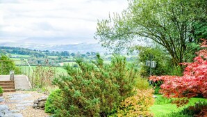 A garden with a stone pathway leading to a wooden deck overlooking a scenic valley. - West Barn - 2 Bedroom Cottage - Llandeilo (Llandeilo)