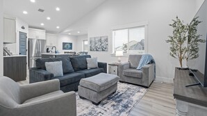A modern living room with a grey sofa, ottoman, and armchair, a flat-screen TV, and a potted plant. - Beautiful & Spacious 3BR Retreat | Clean, Quiet, Sleeps 8 (Idaho Falls)