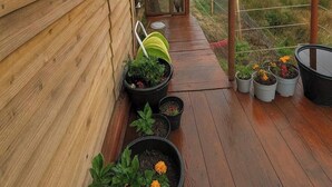 Eine Holzterrasse mit Topfpflanzen und einem kleinen Tisch.